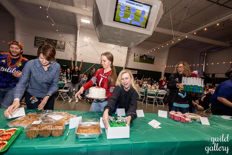A group of people are standing around a table with food.