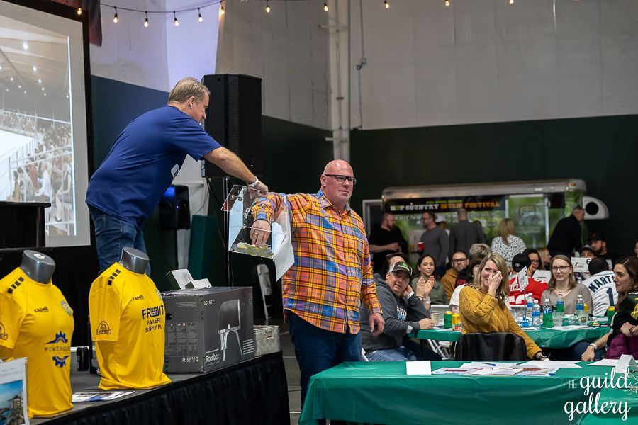 A man is giving a prize to another man in front of a crowd.