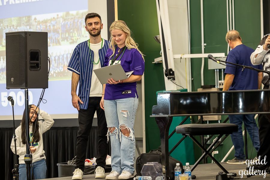 A man and a woman are standing on a stage holding a laptop.
