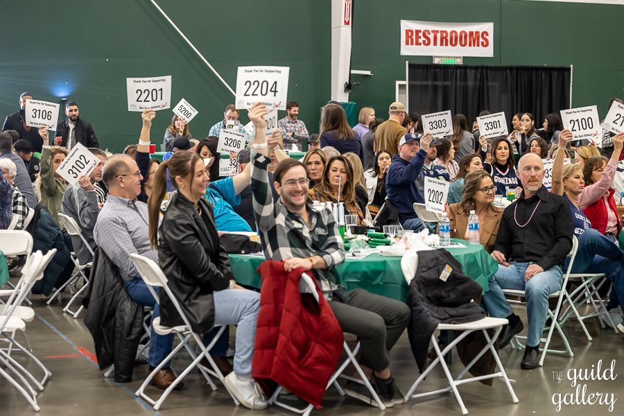 A large group of people are sitting at tables holding up signs.