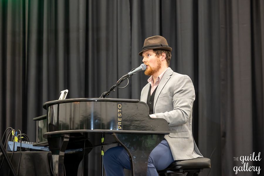 A man is sitting at a piano and singing into a microphone.