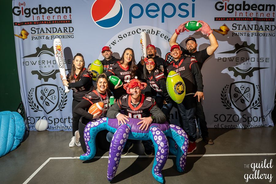 A group of people are posing for a picture in front of a pepsi banner.