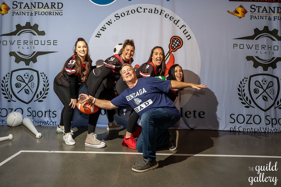 A group of people posing for a picture in front of a sign that says sozo