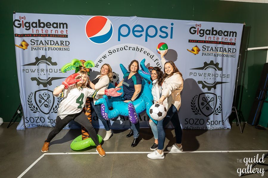 A group of women are posing for a picture in front of a pepsi banner.