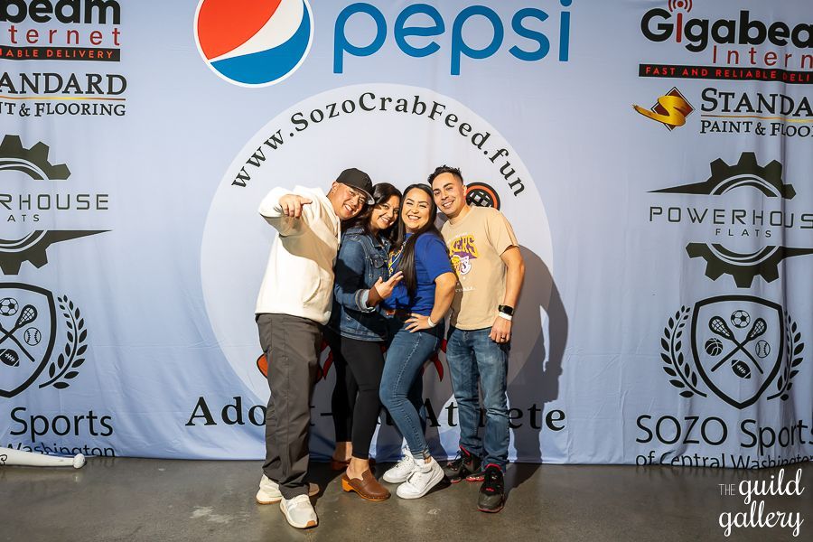 A group of people are posing for a picture in front of a pepsi banner.