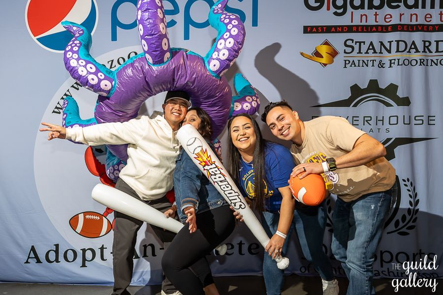 A group of people are posing for a picture in front of a pepsi sign.