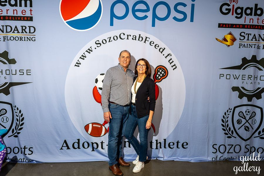 A man and a woman are standing in front of a pepsi banner.