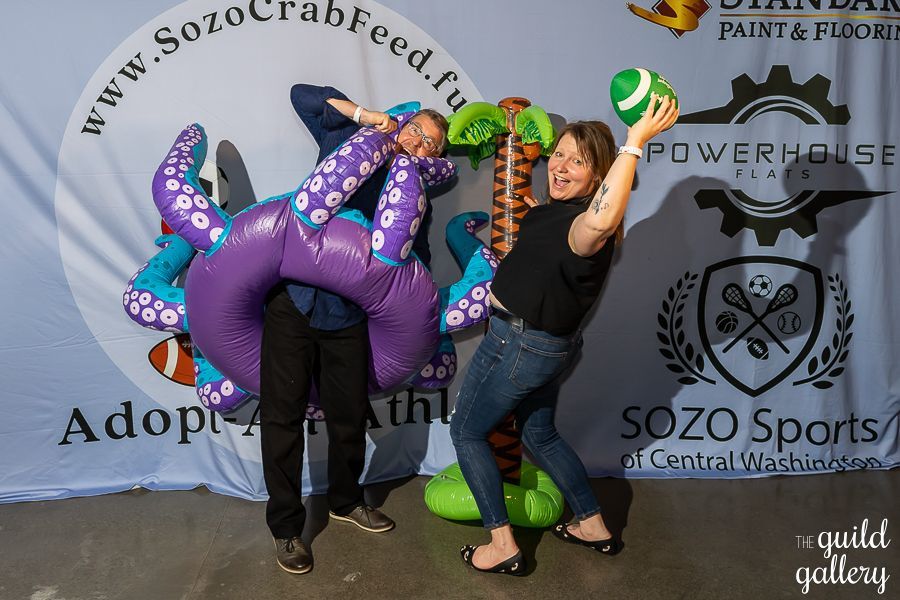 A man and a woman are posing for a picture with an inflatable octopus.