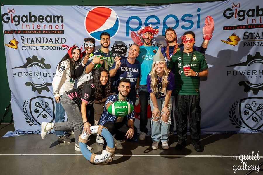 A group of people are posing for a picture in front of a pepsi banner.