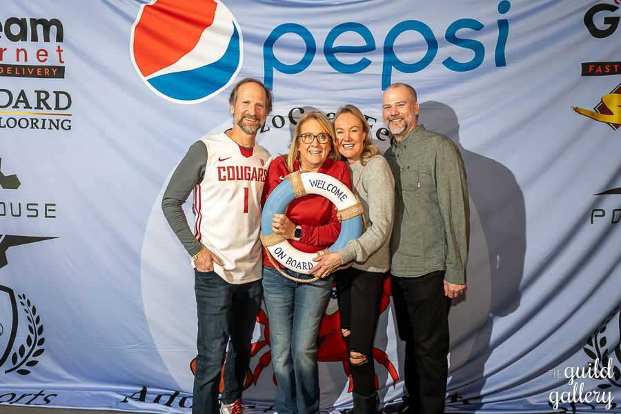 A group of people are posing for a picture in front of a pepsi banner.
