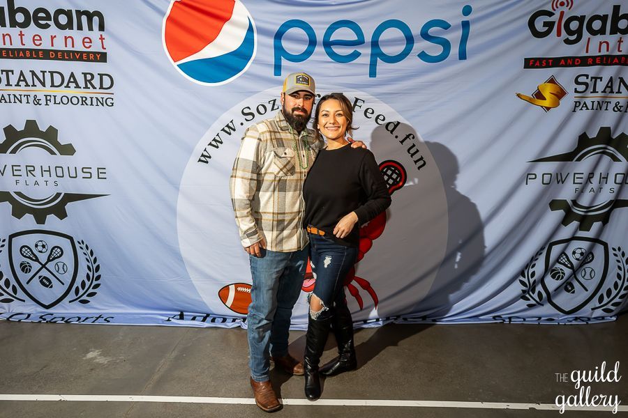 A man and a woman pose in front of a pepsi banner