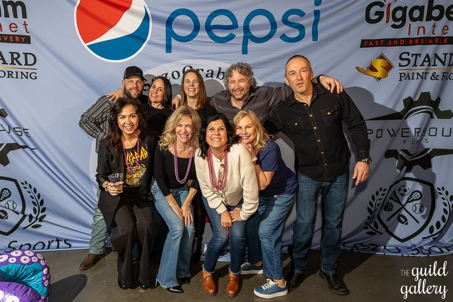 A group of people posing for a picture in front of a pepsi banner.