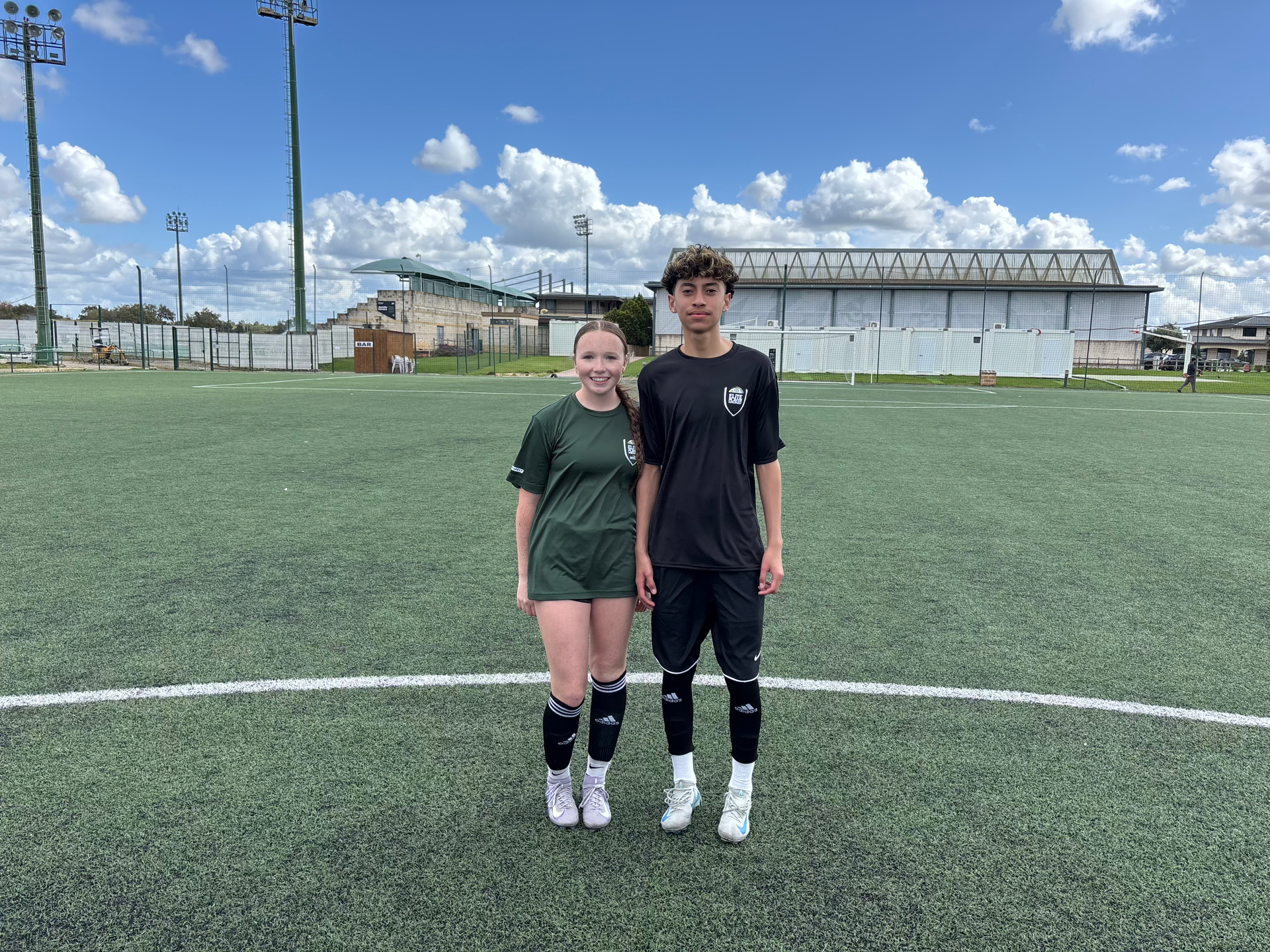 A boy and a girl are standing next to each other on a soccer field.