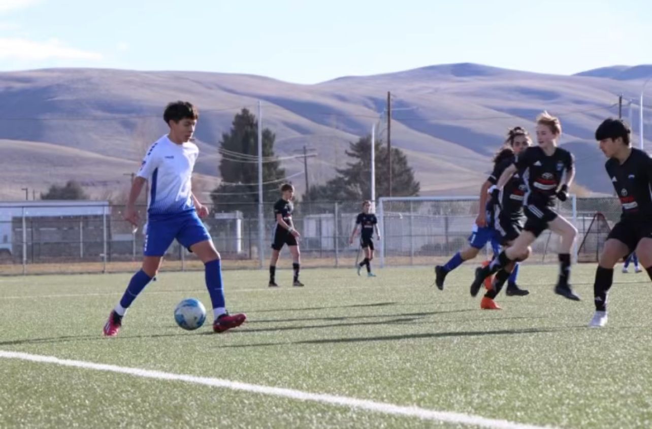 A group of young men are playing soccer on a field.