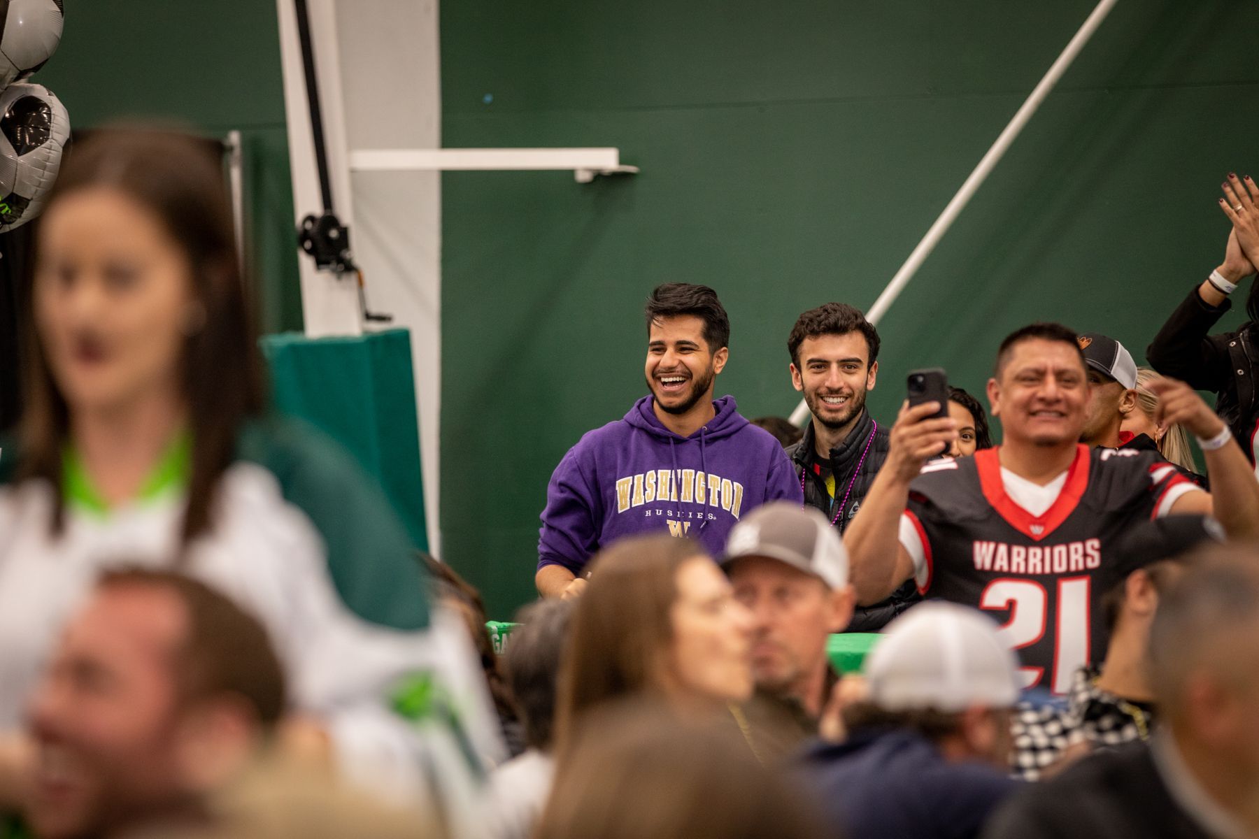 A group of people are sitting in a gym watching a game.