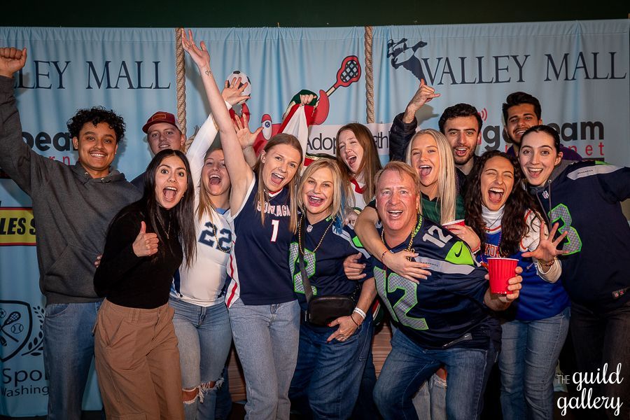 A group of people are posing for a picture in front of a valley mall banner.