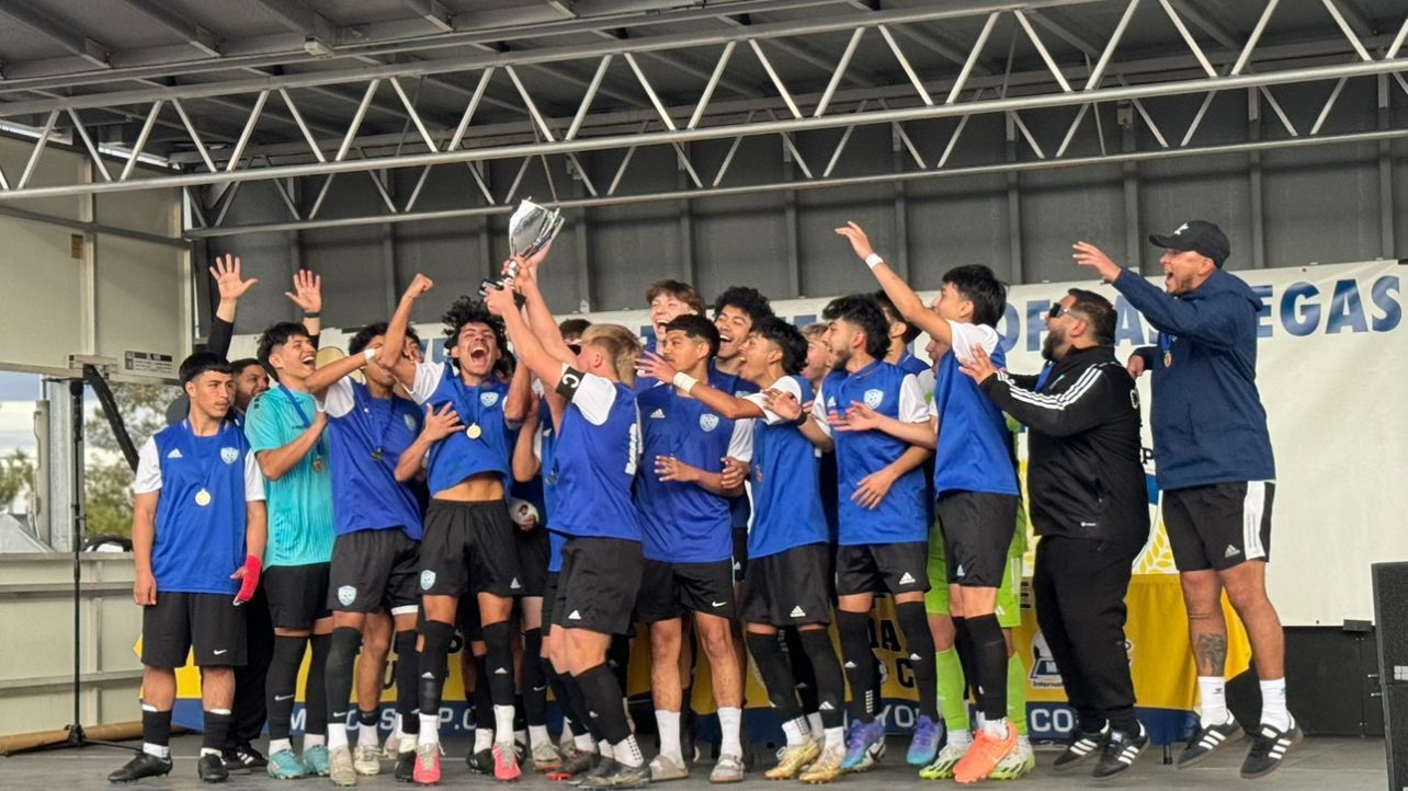 A group of soccer players are standing on a stage holding a trophy.