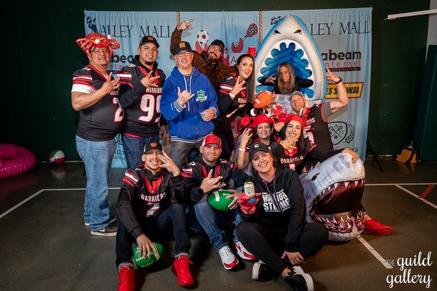 A group of people are posing for a picture in front of a shark balloon.