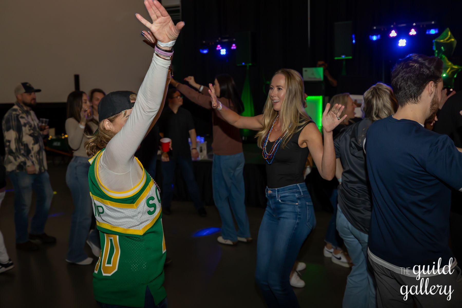 A group of people are dancing in a dark room.