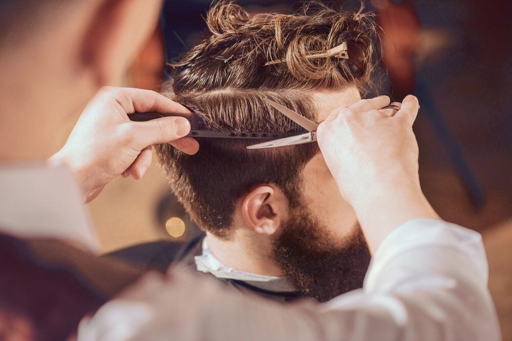 Barber Cutting a Man's Hair With Scissors and Comb in a Salon — Bermann Barbershop in Casey, ACT