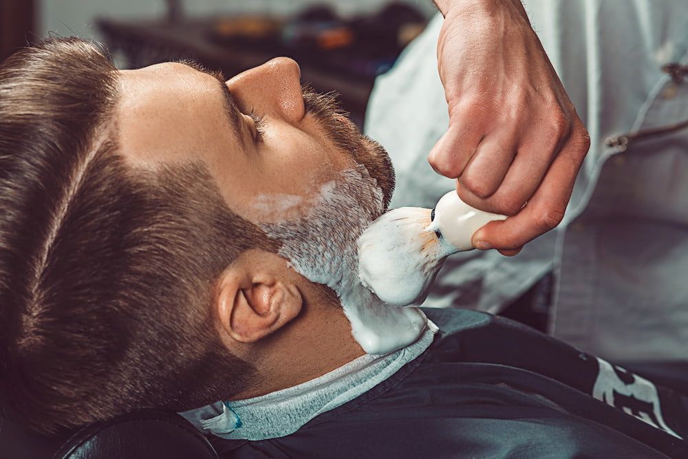 A Barber Applies Shaving Cream to a Man's Beard With a Brush — Bermann Barbershop in Casey, ACT