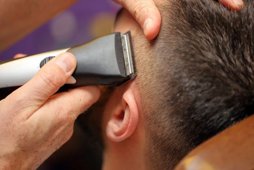 Hair Clippers Trimming a Man's Hair Around His Ear — Bermann Barbershop in Gungahlin, ACT