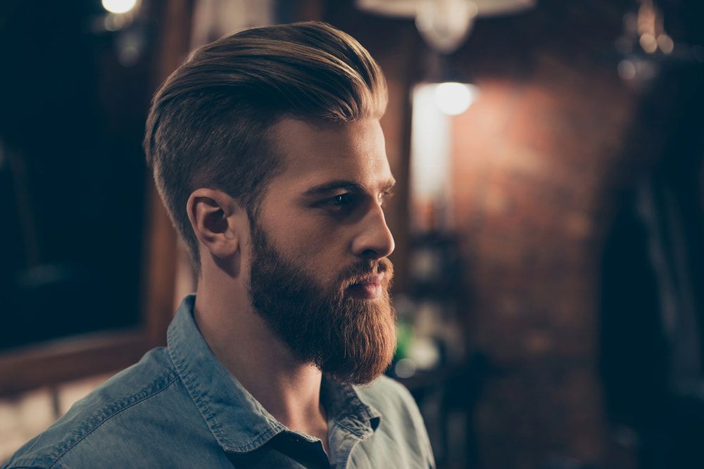 Man With Blonde Hair and Full Beard in a Dim Setting — Bermann Barbershop in Casey, ACT