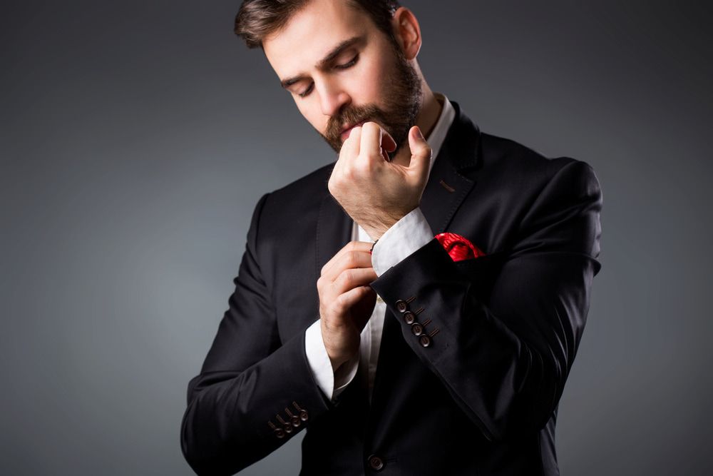 Man in a Suit Adjusting His Cuff With a Red Pocket Square — Bermann Barbershop in Casey, ACT