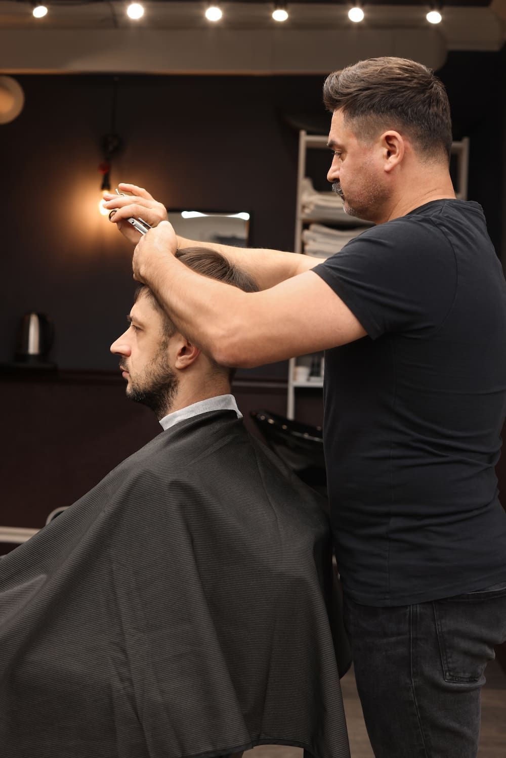Barber Giving a Haircut to a Customer in a Salon; Black Attire — Bermann Barbershop in Nicholls, ACT