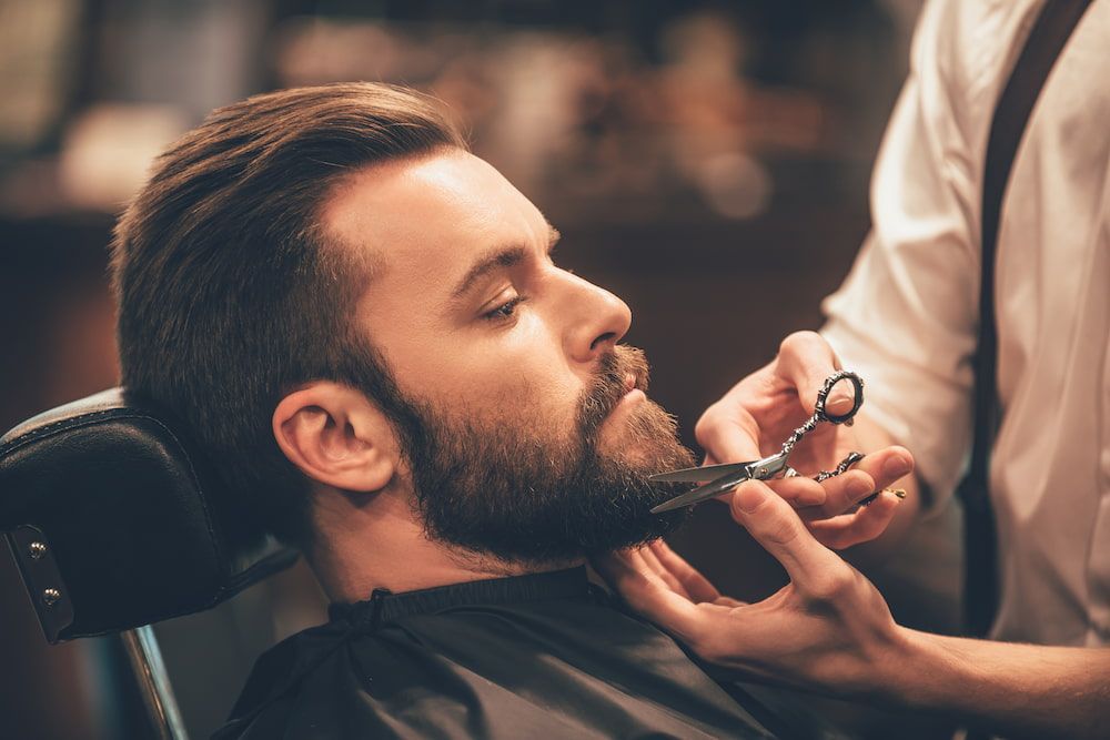 Man Getting Beard Trimmed With Scissors by Barber in a Barber Shop — Bermann Barbershop in Casey, ACT