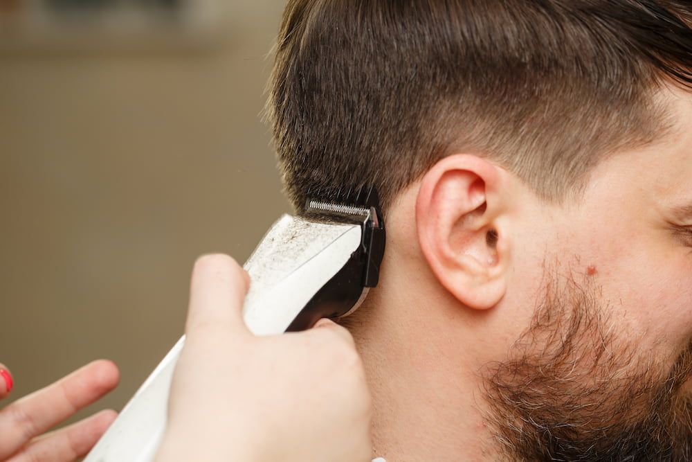 a Person Getting a Haircut, Clippers Trimming Hair Near Ear — Bermann Barbershop in Casey, ACT