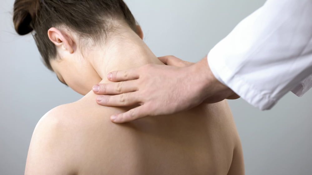 A Woman Is Getting A Neck Massage From A Doctor — Grays Chiropractic Centre In Rural View, QLD