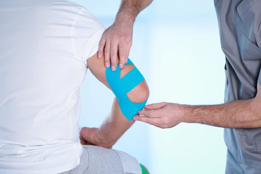 A Man Is Getting A Bandage On His Elbow — Grays Chiropractic Centre In Rural View, QLD