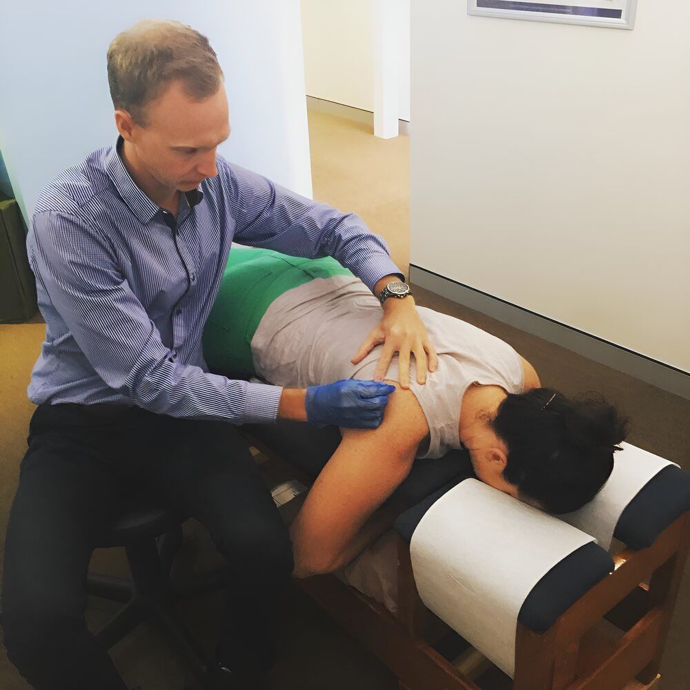 A Man Is Giving A Woman A Massage On A Table — Grays Chiropractic Centre In Andergrove, QLD