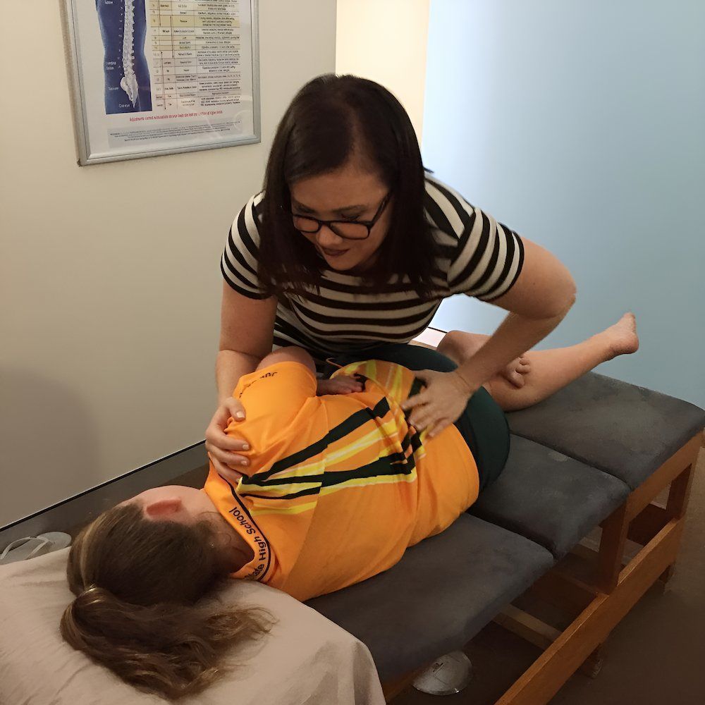 A Woman Is Stretching A Child's Arm On A Table — Grays Chiropractic Centre In Bucasia, QLD