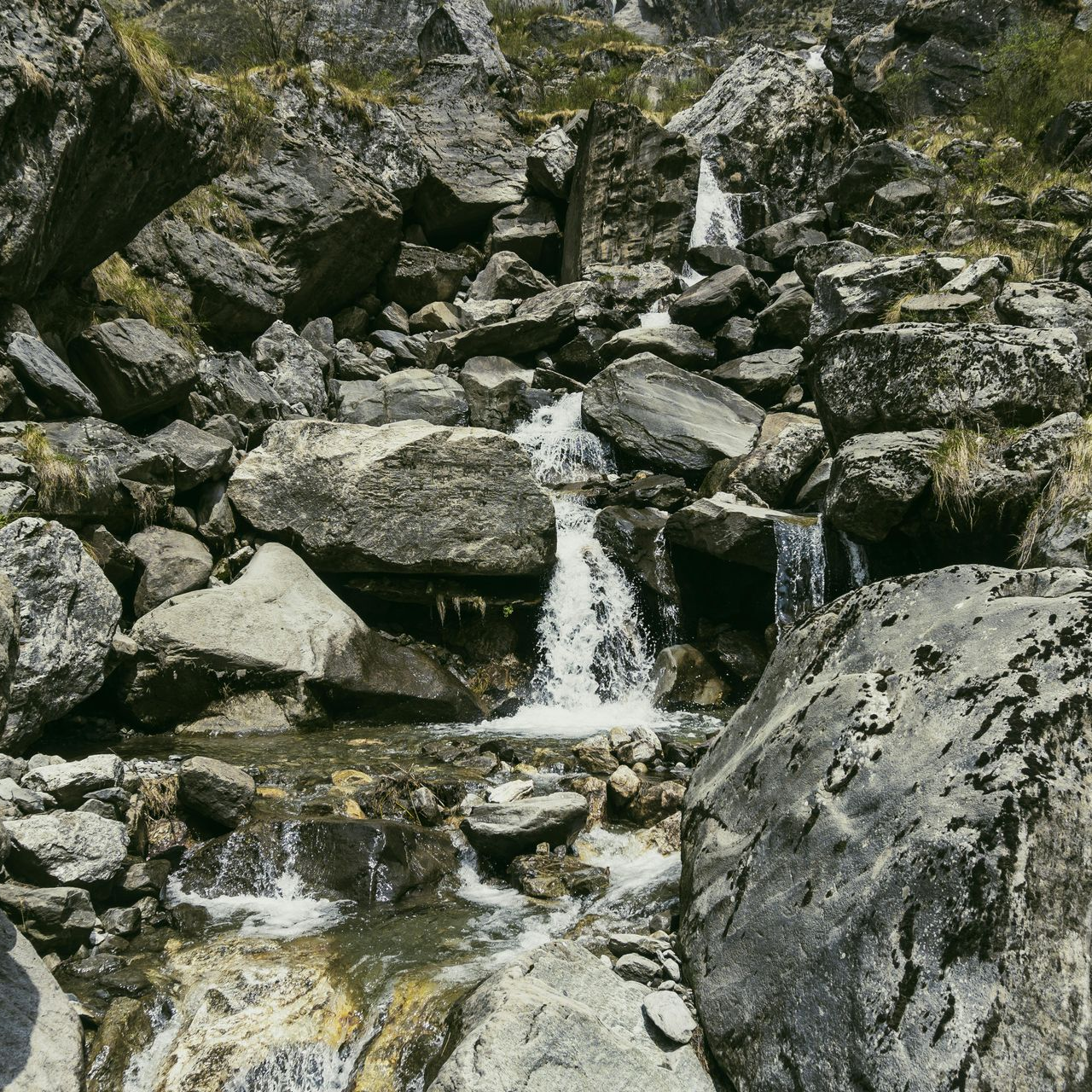 Waterfall cascading through rocky terrain. Water flows over gray and white stones.