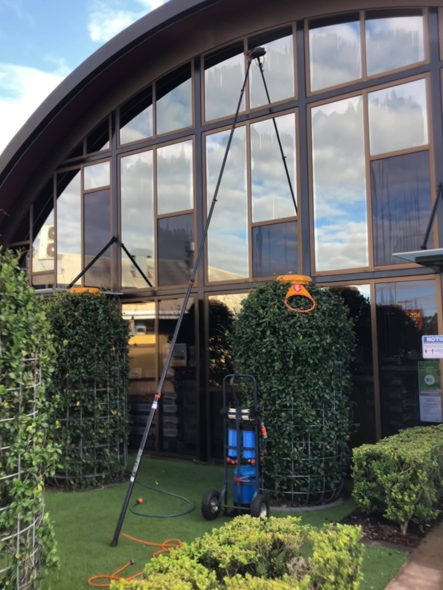 Worker Cleaning Windows of Office Building — Cleaning Company in Bundaberg