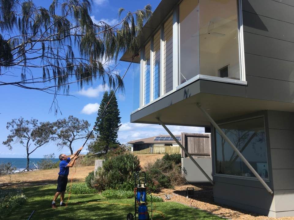 Male Worker Cleaning Window Exterior — Cleaning Company in Bundaberg