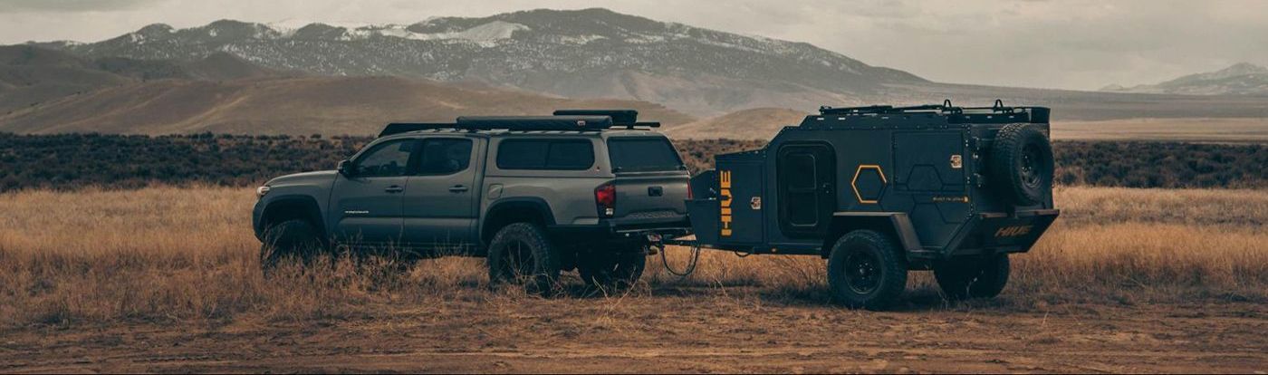 A truck with a trailer attached to it is parked in a field.