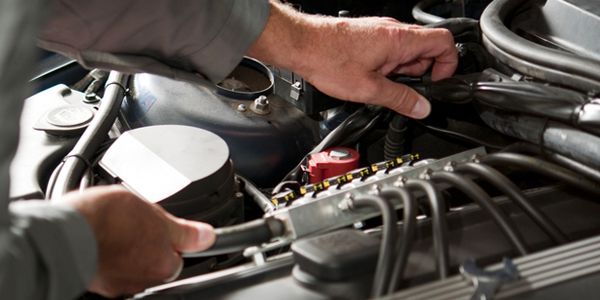 A man is working on the engine of a car.