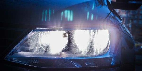 A close up of a car headlight in the dark.