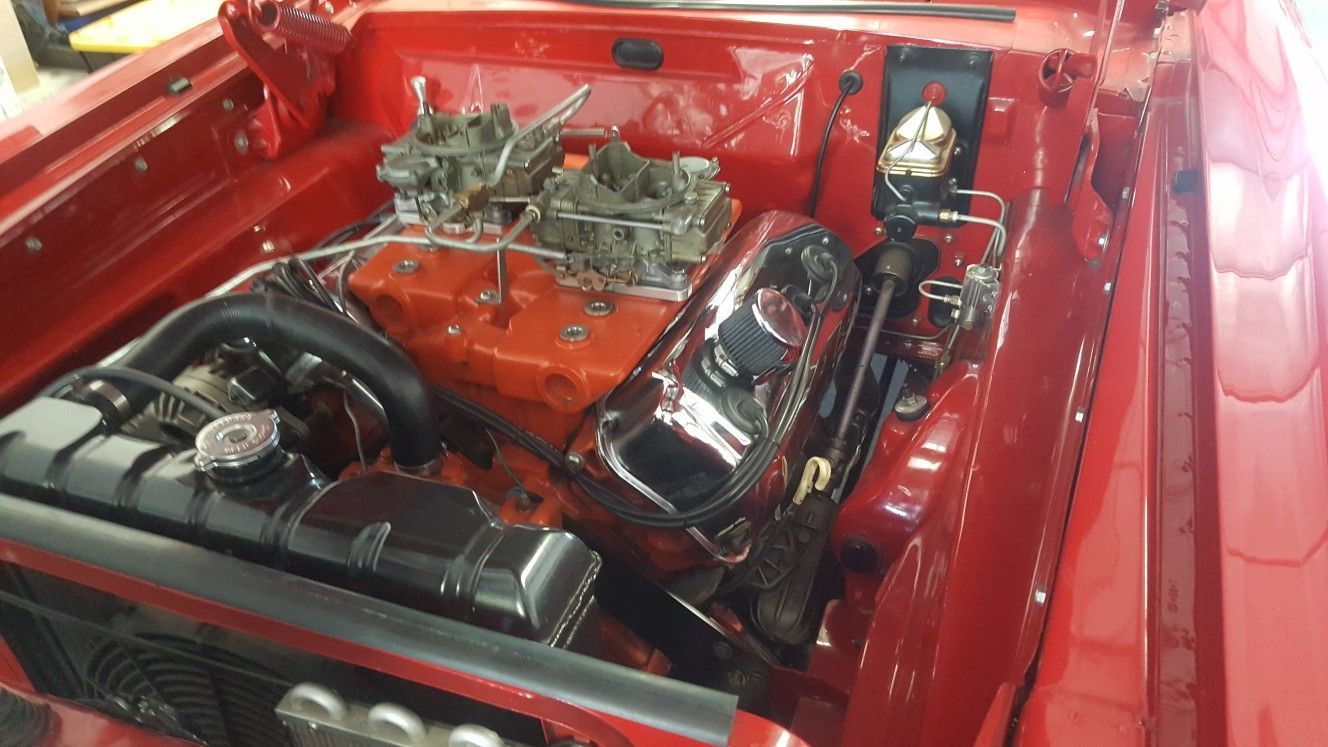 The engine of a red car is shown in the hood.