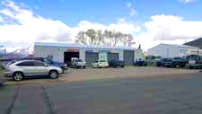 A row of cars are parked in front of a building.