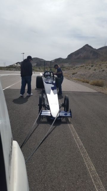 A race car is being towed down a road by two men