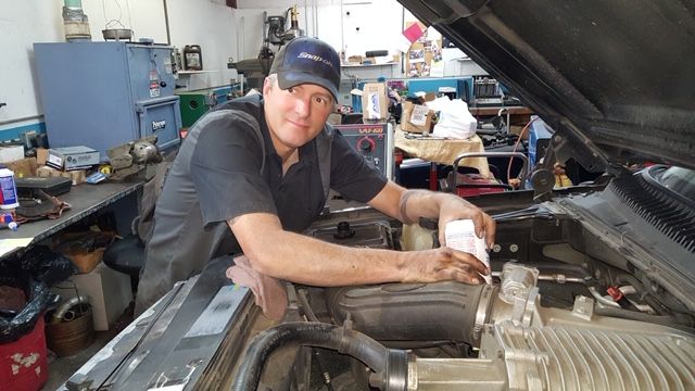 A man is working on the engine of a car in a garage.