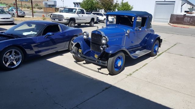 A blue car is parked next to a black car in a parking lot.