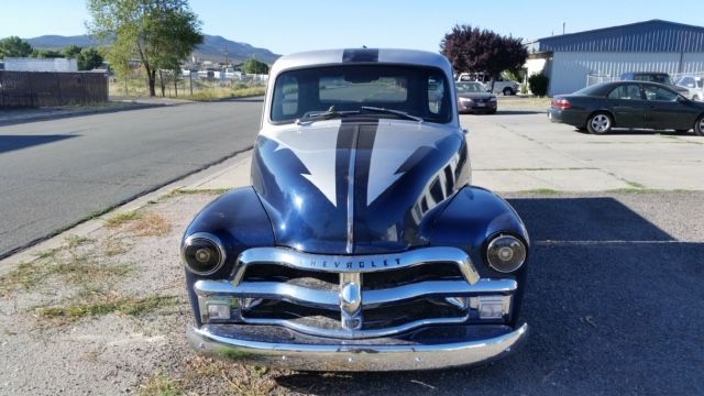 A blue and white chevrolet truck is parked on the side of the road