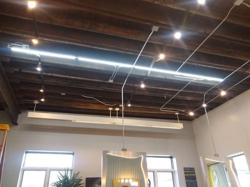 Exposed wood ceiling with pendant lights and a long fluorescent light fixture in a room with windows.
