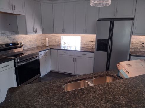 Kitchen with gray cabinets, dark countertop, stainless steel appliances, and a double sink.