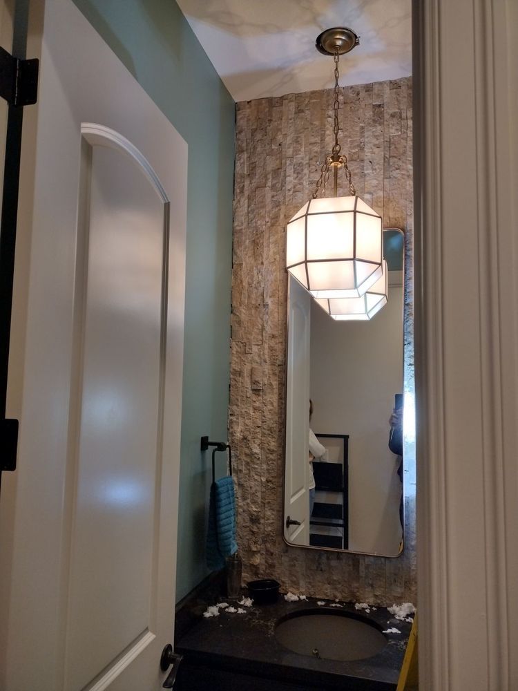 Small powder room with textured wall, mirror, pendant light, and sink. White door on the left. Light green and white walls.